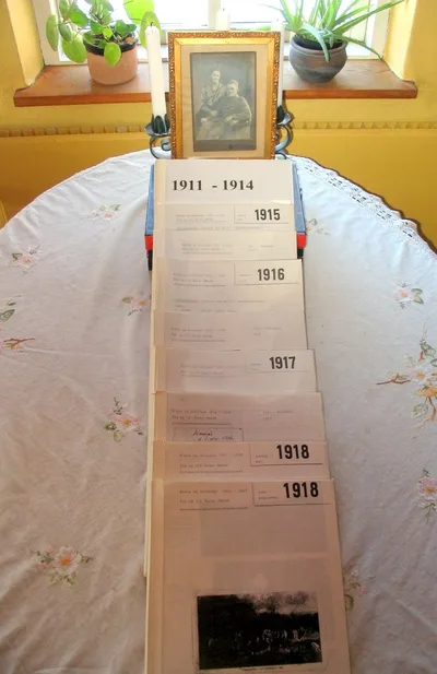 Physical letter binders organized by year 1911-1918, with framed photo